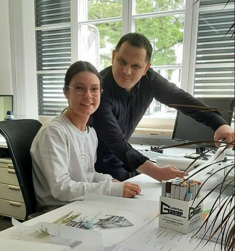 Eine Schülerin sitzt am Arbeitsplaz mit Ihrem Betreueuer